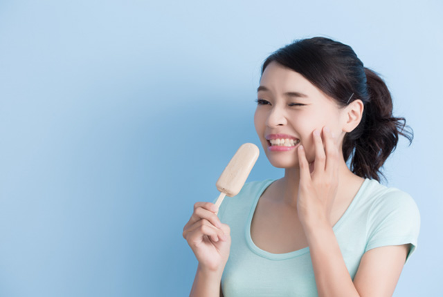 アイスを食べながら頬に手を当てる女性